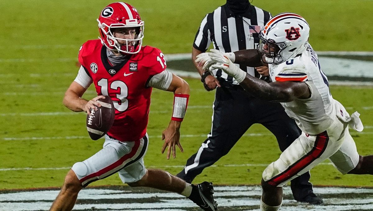 Georgia Bulldogs quarterback Stetson Bennett (13) escapes the pressure of Auburn Tigers Auburn Tigers linebacker Owen Pappoe (0) during the second half at Sanford Stadium.
