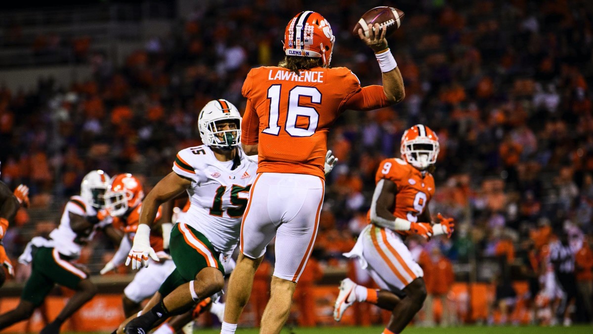 Clemson Tigers quarterback Trevor Lawrence (16) throws to running back Travis Etienne (9) against Miami Hurricanes defensive line Jaelan Phillips (15) during the first quarte at Memorial Stadium.