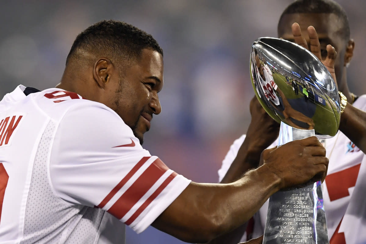 Former Giants player Michael Strahan walks onto the field with the Vince Lombardi Trophy from Super Bowl XLII during the halftime ceremony in the game against the Lions at MetLife Stadium, Sept. 18, 2017.