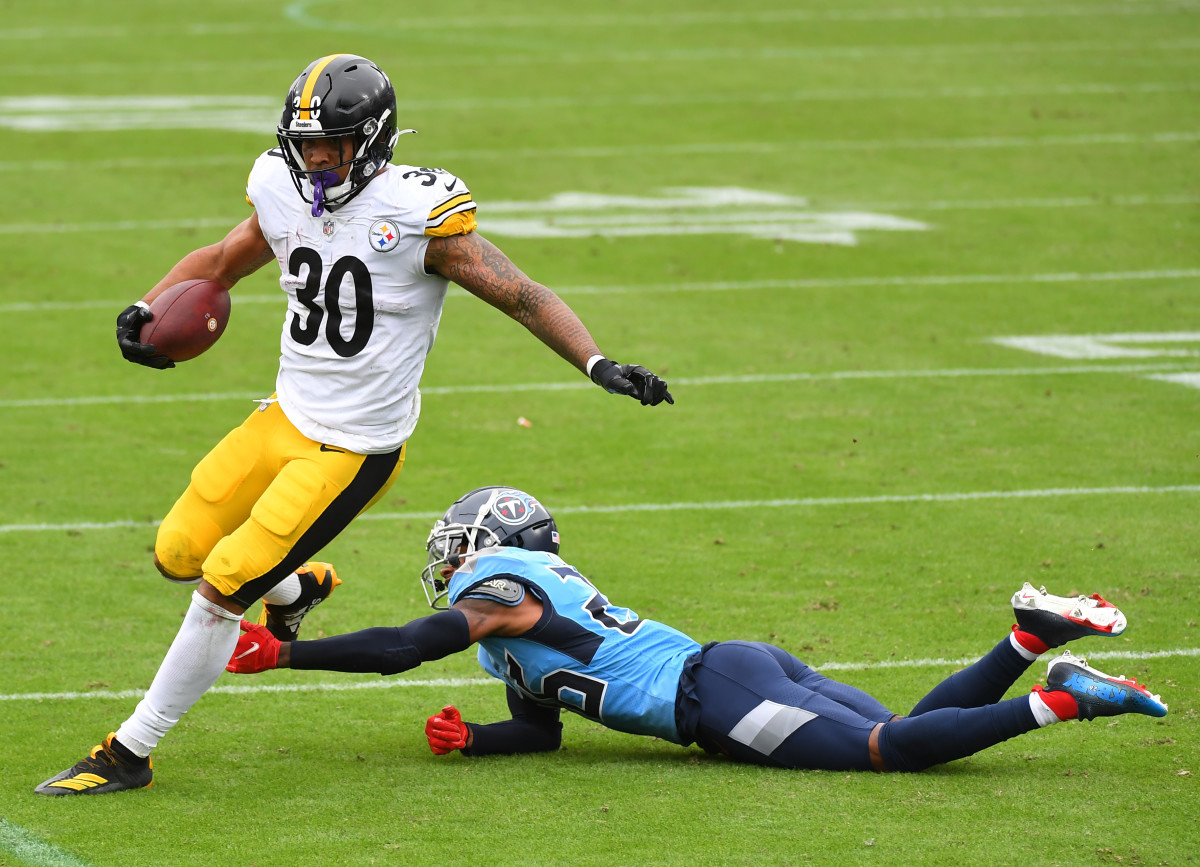 Steelers running back James Conner (30) runs for a short gain past Titans cornerback Kristian Fulton (26) during the first half at Nissan Stadium. 