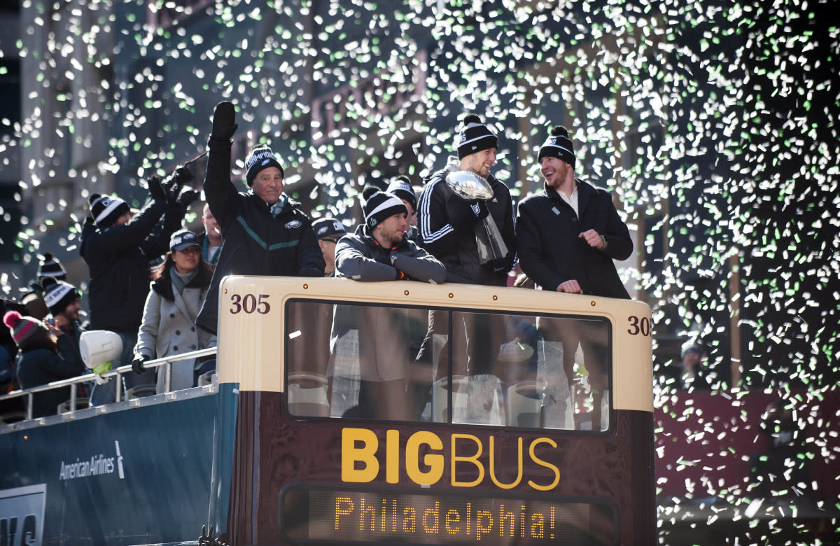 Confetti falls as (from right) QB Carson Wentz, backup QB Nate Sudfeld, Super Bowl MVP Nick Foles and owner Jeffrey Lurie ride a float during the Eagles Super Bowl LII victory parade, Feb. 8, 2018.