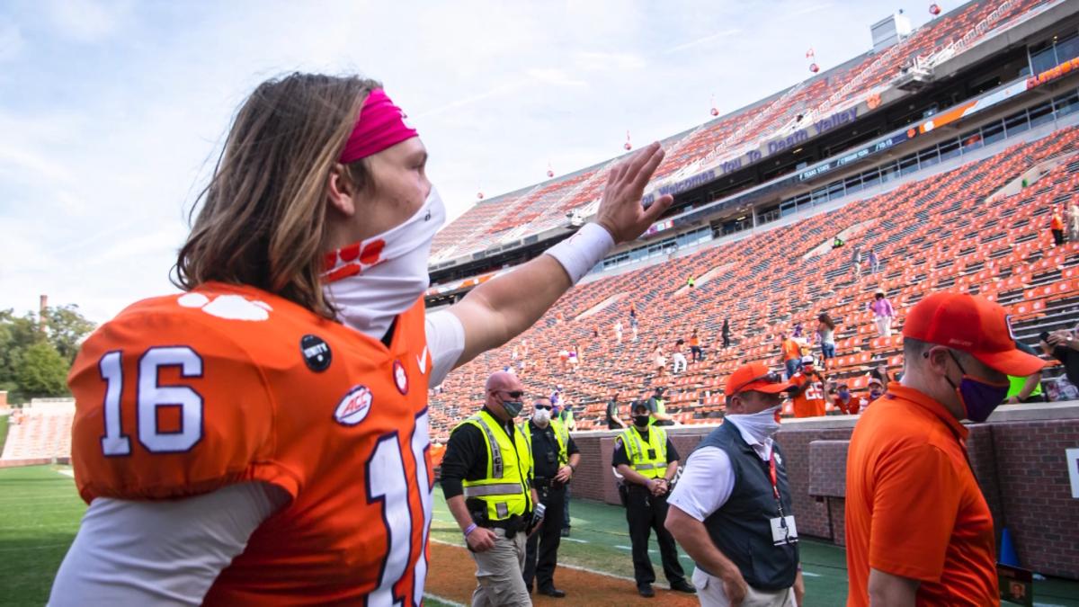 Clemson QB Trevor Lawrence waves to fans while wearing a mask