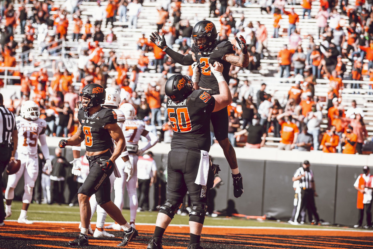 Oklahoma State center Ry Schneider lifts up wide receiver Tylan Wallace in celebration after a touchdown against Texas.