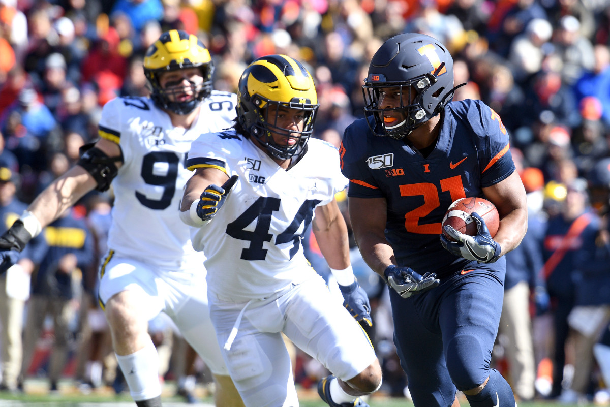 Illinois Fighting Illini running back Ra'Von Bonner (21) is chased by Michigan Wolverines linebacker Cameron McGrone (44) and linebacker Khaleke Hudson (7) during the first half of a 2019 game at Memorial Stadium.