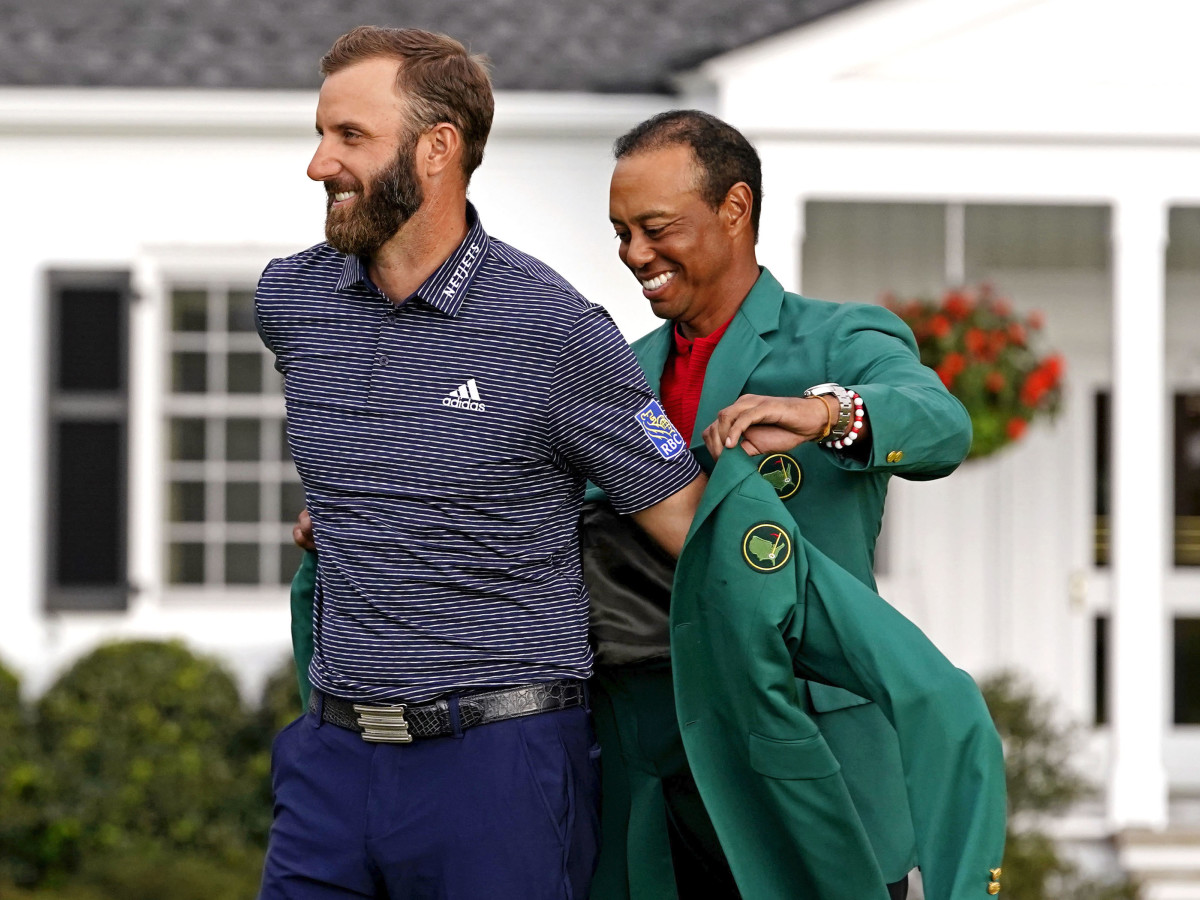 2019 Masters champion Tiger Woods presents Dustin Johnson with the green jacket after winning The Masters golf tournament