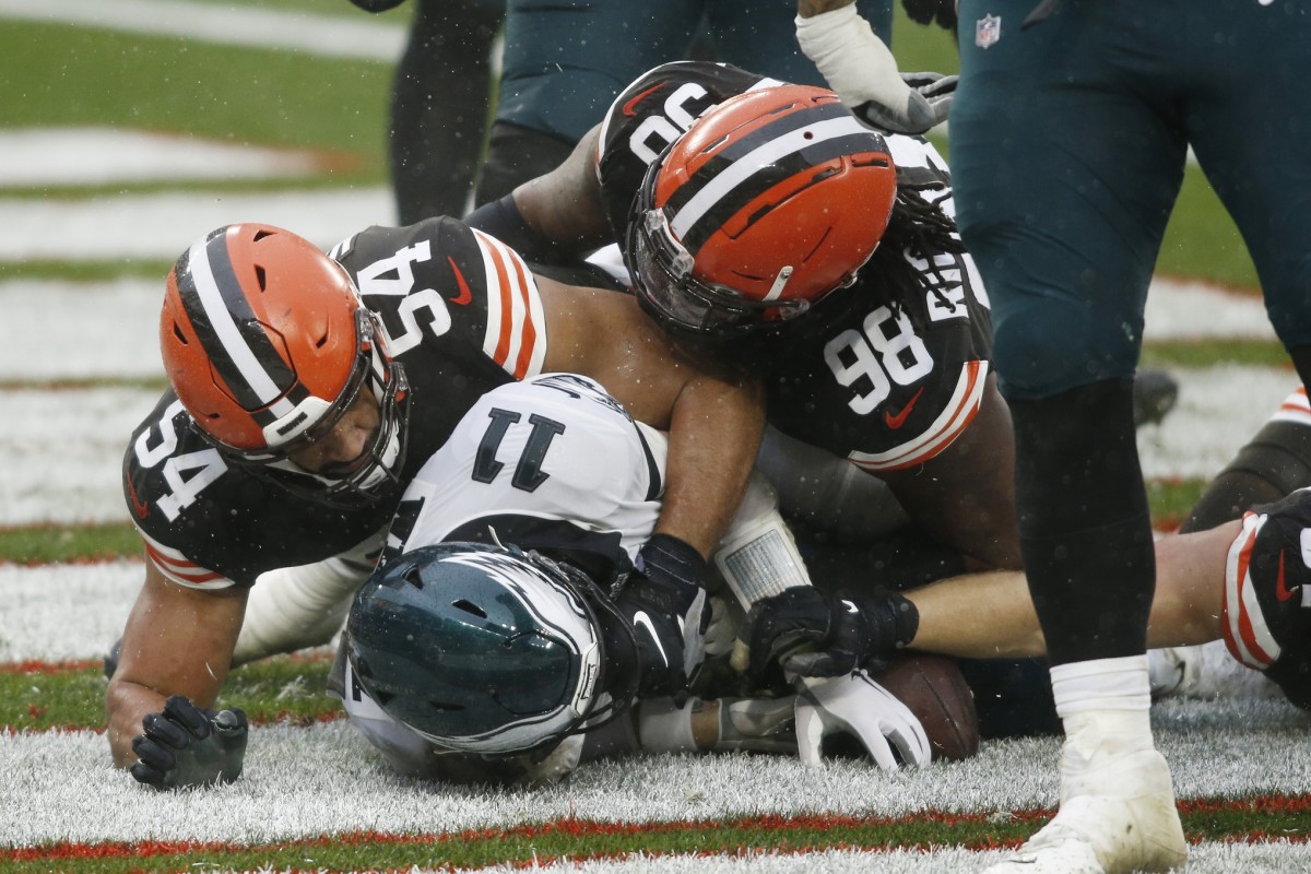 Nov 22, 2020; Cleveland, Ohio, USA; Cleveland Browns defensive end Olivier Vernon (54) and defensive tackle Sheldon Richardson (98) lie on top of Philadelphia Eagles quarterback Carson Wentz (11) after Wentz was sacked for a safety during the second half at FirstEnergy Stadium.