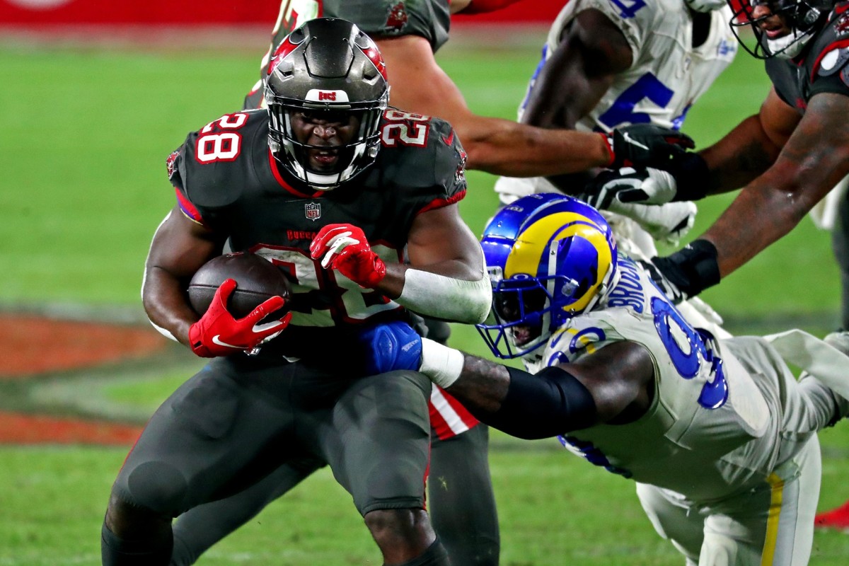 Nov 23, 2020; Tampa, Florida, USA; Tampa Bay Buccaneers running back Leonard Fournette (28) runs the ball against Los Angeles Rams defensive end Michael Brockers (90) during the fourth quarter at Raymond James Stadium. Man