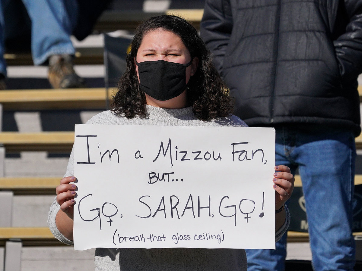 A fan holds a sign that says "I'm a Mizzou Fan But....Go, Sarah, Go!"