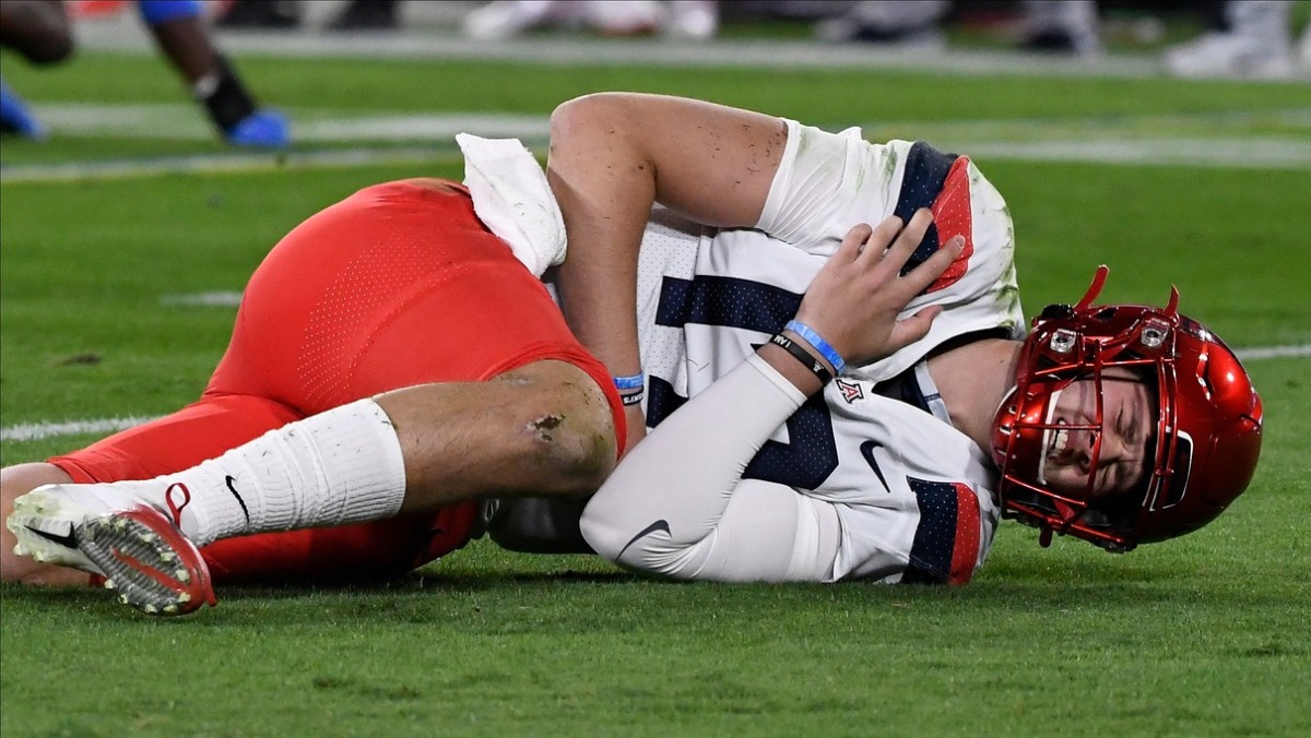 Nov 28, 2020; Pasadena, California, USA; Arizona Wildcats quarterback Grant Gunnell (17) grabs his shoulder after getting hit on the first play of the game against the UCLA Bruins at Rose Bowl.