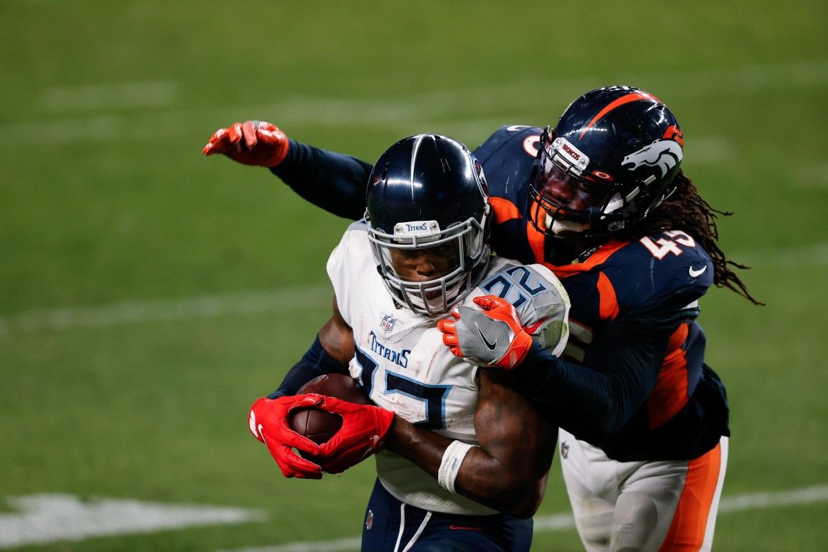 Tennessee Titans running back Derrick Henry (22) is tied up by Denver Broncos linebacker Alexander Johnson (45) in the fourth quarter at Empower Field at Mile High.