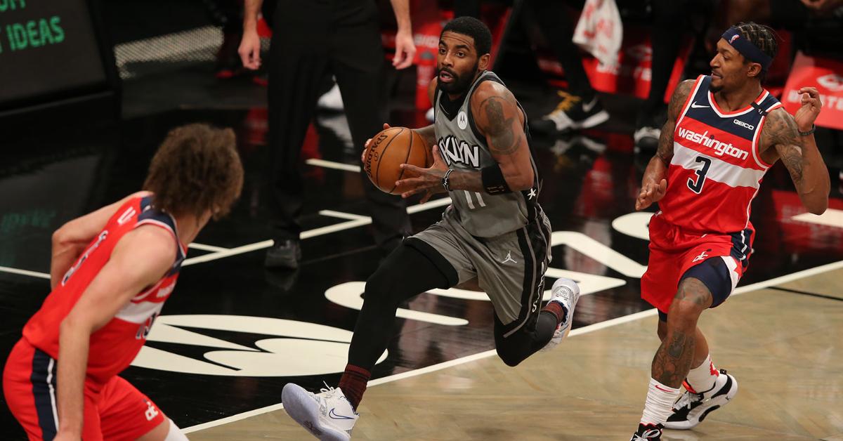 Brooklyn Nets point guard Kyrie Irving (11) drives to the basket against Washington Wizards center Robin Lopez (15) and shooting guard Bradley Beal (3) during the second quarter at Barclays Center.