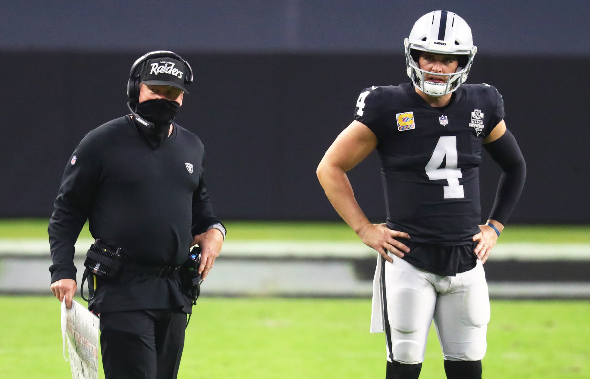 Jon Gruden and Derek Carr talk on the field before a Raiders game during the 2020 season
