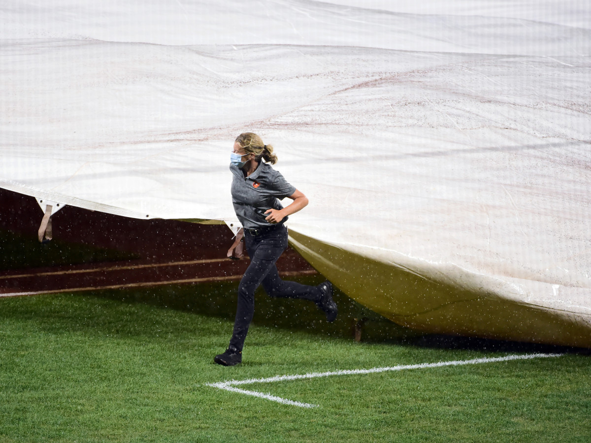 Jul 30, 2020; Baltimore, Maryland, USA; Baltimore Orioles head groundskeeper Nicole Sherry (center) covers the field with the tarp during a rain delay in a game against the New York Yankees at Oriole Park at Camden Yards.