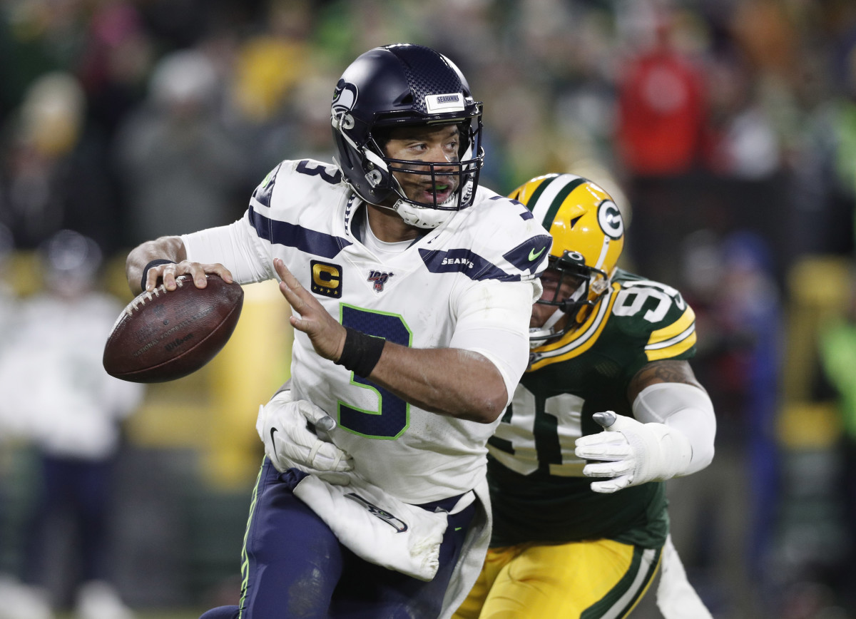 Seattle Seahawks quarterback Russell Wilson (3) runs away from Green Bay Packers outside linebacker Preston Smith (91) in the third quarter of a NFC Divisional Round playoff football game at Lambeau Field.
