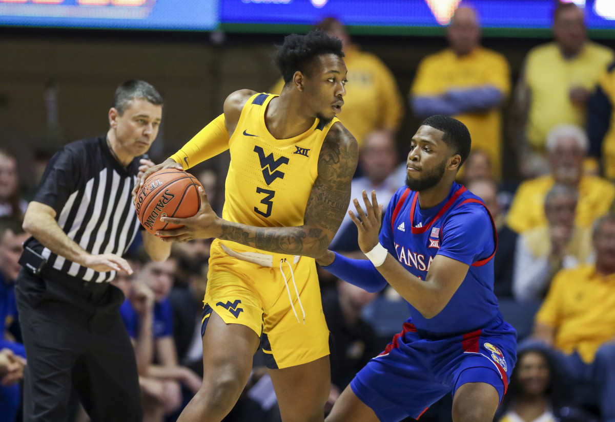 West Virginia Mountaineers forward Gabe Osabuohien (3) looks to pass while defended by Kansas Jayhawks guard Isaiah Moss (4) during the first half at WVU Coliseum.