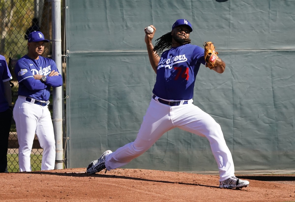 Feb 14, 2020; Glendale, Arizona, USA; Los Angeles Dodgers relief pitcher Kenley Jansen (74) throws in the bullpen as manager Dave Roberts (left) looks on during spring training. Mandatory Credit: Rick Scuteri-USA TODAY Sports