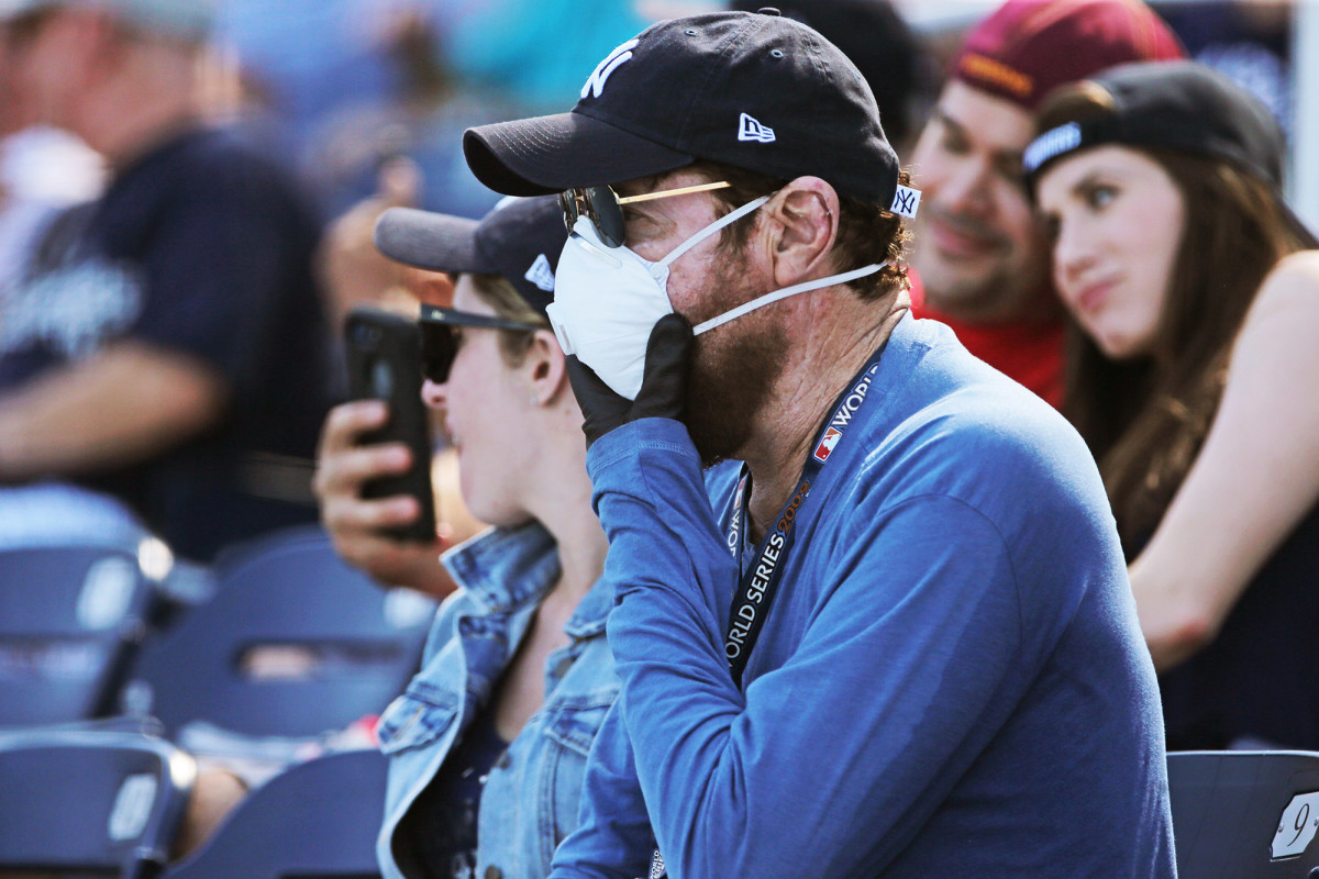 A fan wears a mask and gloves during a spring training game between the Nationals and the Yankees in Florida.
