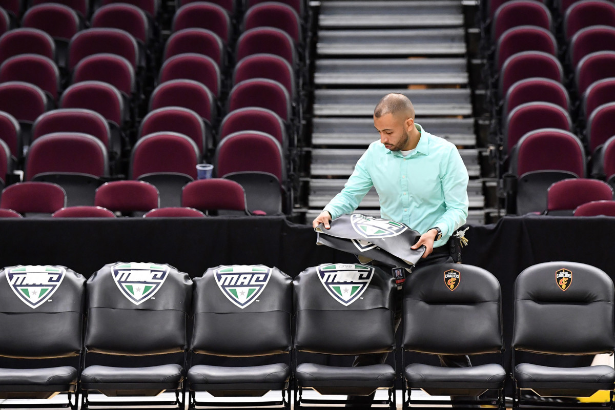 A worker removes the insignia of the Mid-American Conference from the bench chairs after the MAC tournament is cancelled.