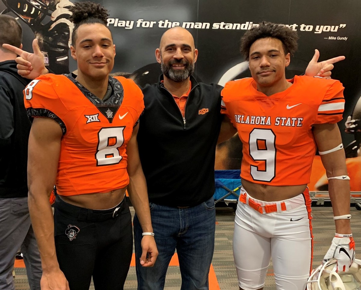Kasey Dunn standing between Blaine (left) and Bryson (right) Green inside the Oklahoma State locker room.