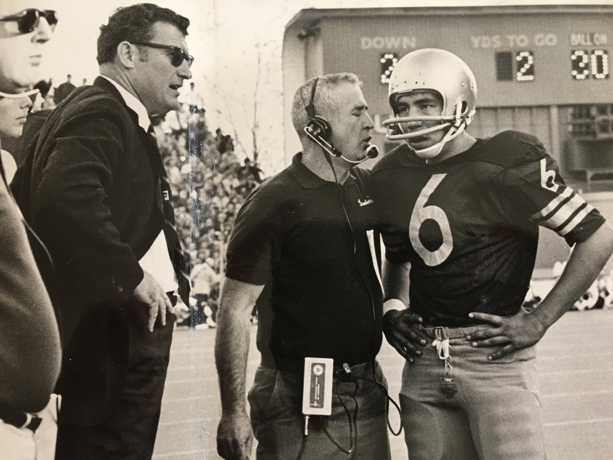 Sonny Sixkiller listens to assistant coach Jerry Cheek while Husky coach Jim Owens looks on.