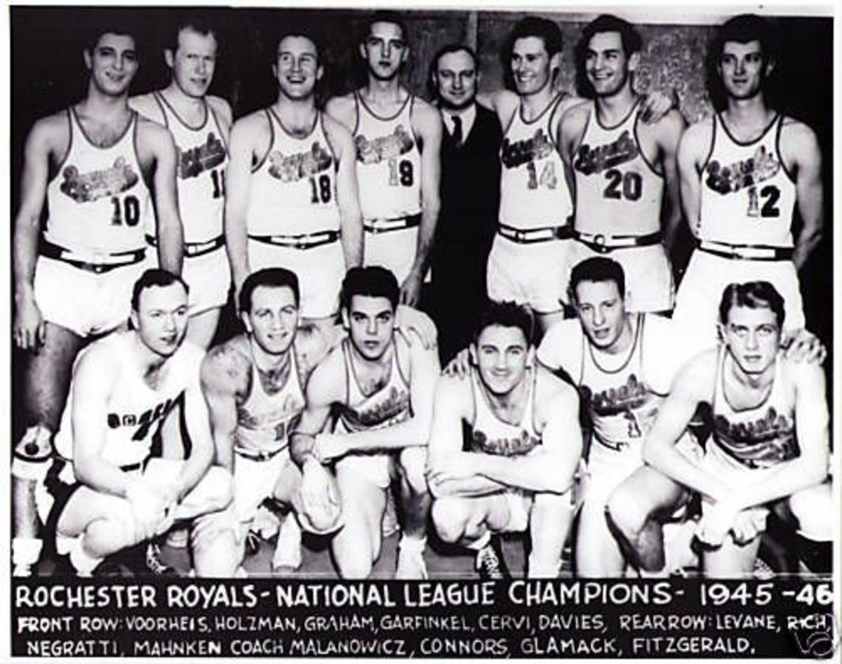 Before he was an Hall of Game QB for the Cleveland Browns, Otto Graham (kneeling, third from left) was a pro basketball champion with the Rochester Royals. Hall of Fame coach Red Holzman has his arm around Graham.
