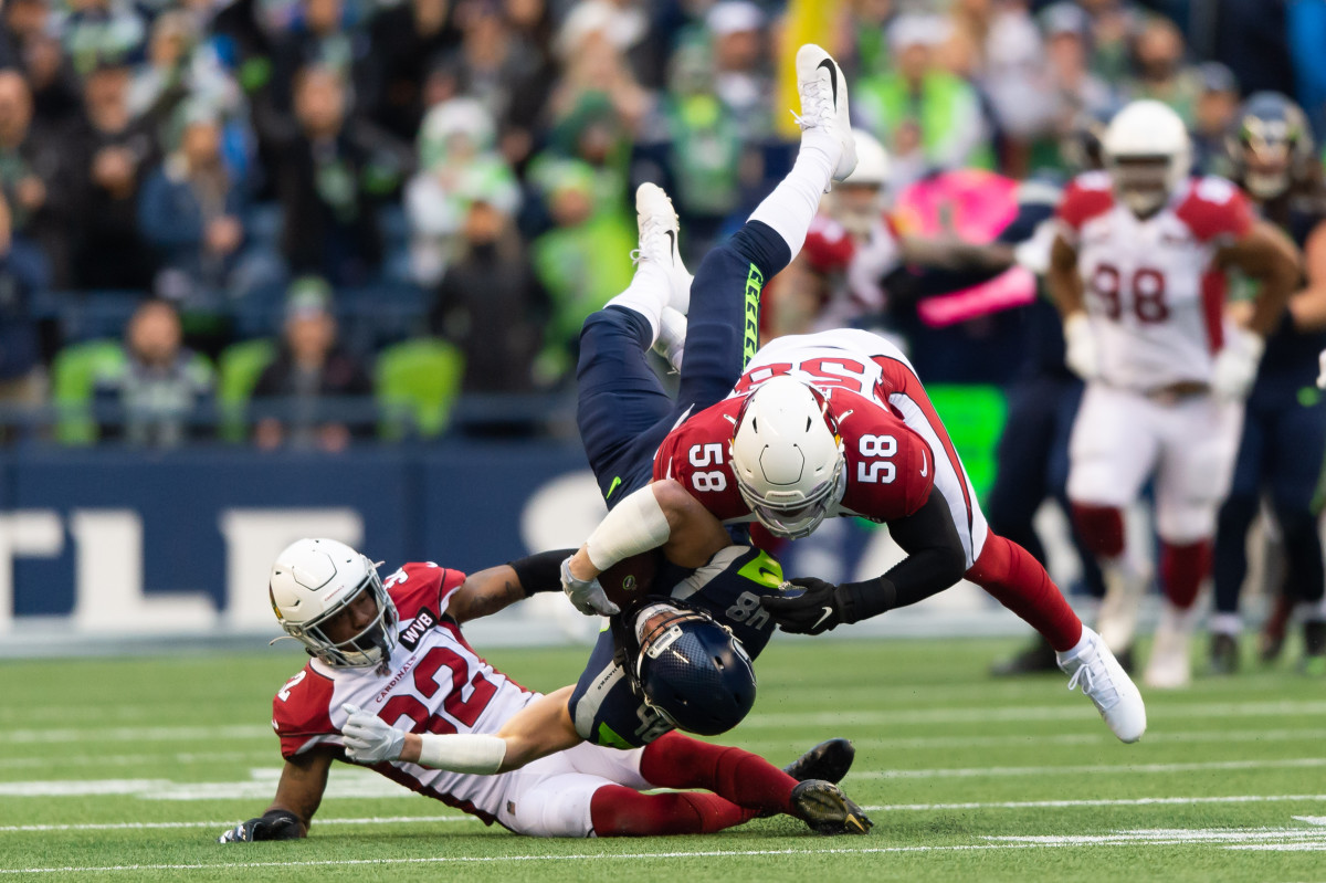 Cardinals strong safety Budda Baker (32) and middle linebacker Jordan Hicks (58) tackle Seahawks tight end Jacob Hollister (48) during the first half of a 2019 Cardinals victory in Seattle.