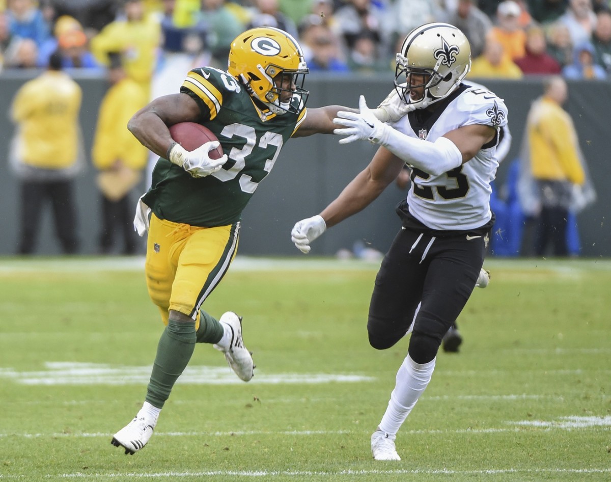 Oct 22, 2017; Green Bay, WI, USA; Green Bay Packers running back Aaron Jones (33) tries to break a tackle by New Orleans Saints cornerback Marshon Lattimore (23) in the third quarter at Lambeau Field. Mandatory Credit: Benny Sieu-USA TODAY Sports