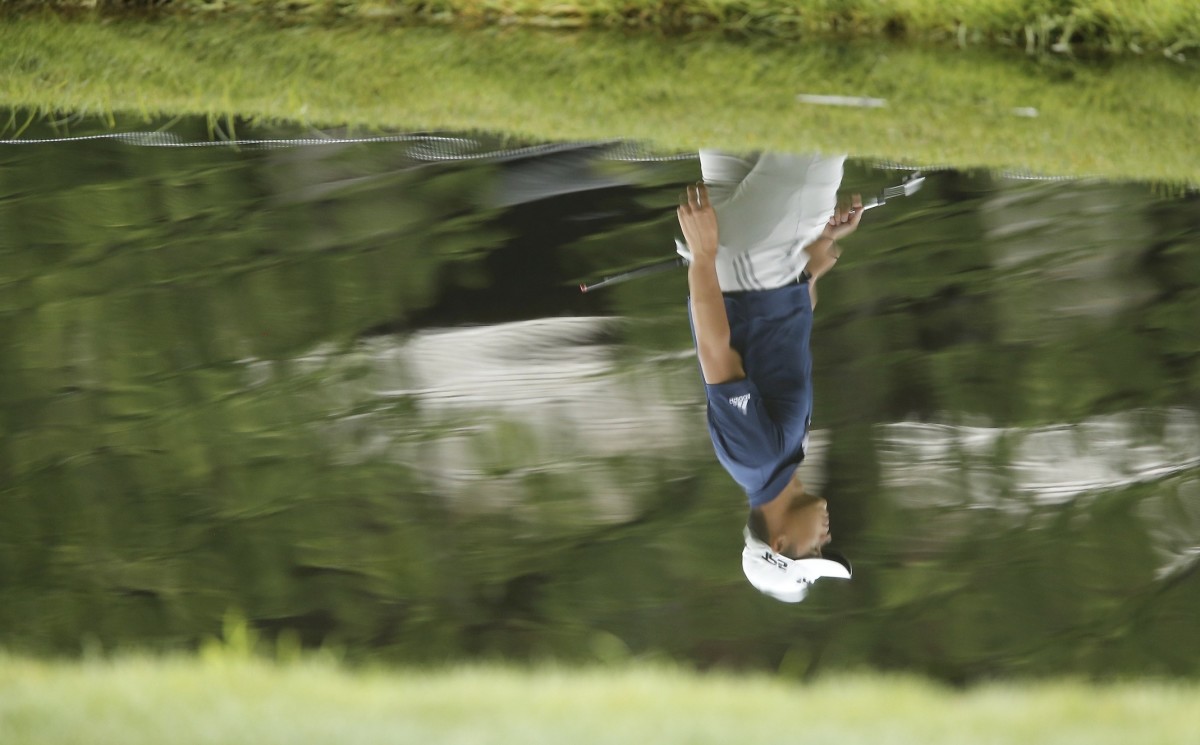 Collin Morikawa's image in reflected in the water at Muirfield Village