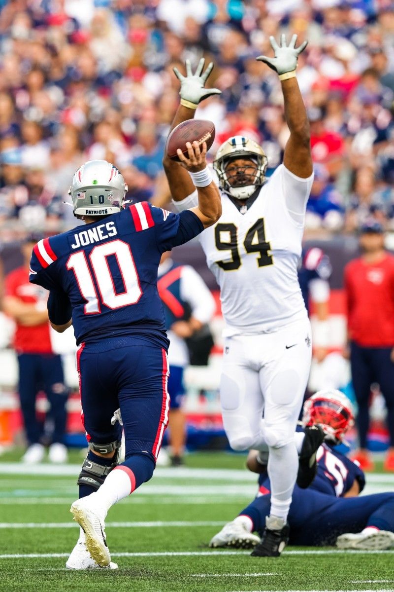 New England Patriots quarterback Mac Jones (10) passes with pressure from New Orleans Saints defensive end Cameron Jordan (94