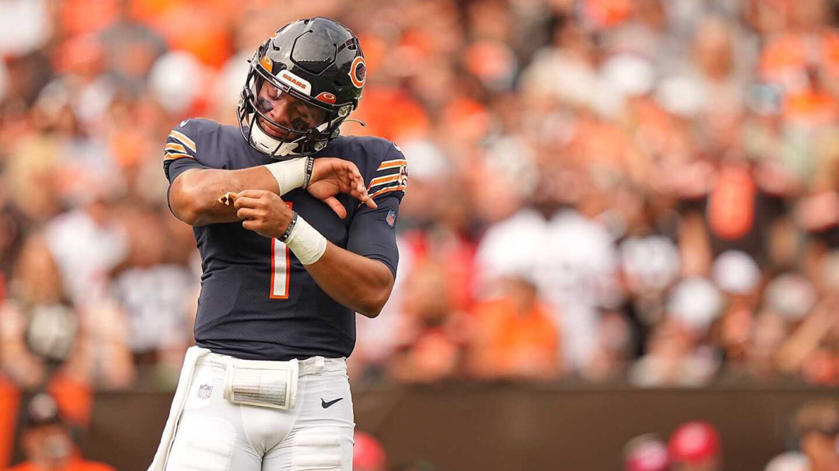Justin Fields looks down at his arm between plays in a game against the Browns