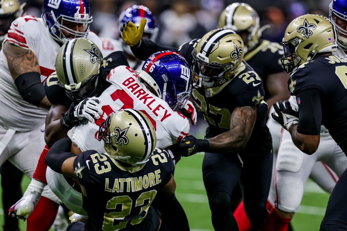 Giants running back Saquon Barkley (26) is tackled by New Orleans Saints cornerback Marshon Lattimore (23) and safety Malcolm Jenkins (27). Mandatory Credit: Stephen Lew-USA TODAY Sports