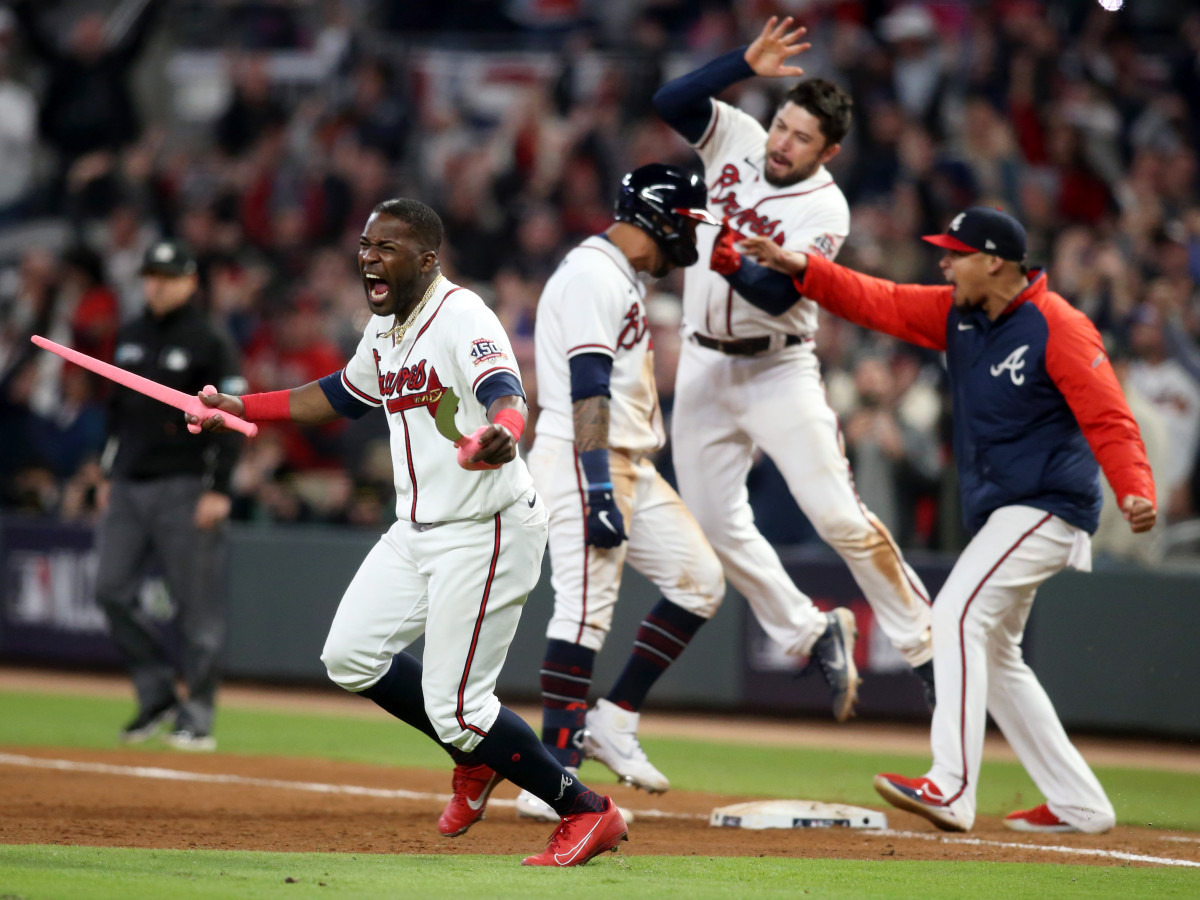 Oct 17, 2021; Cumberland, Georgia, USA; Atlanta Braves center fielder Guillermo Heredia (38) celebrates with toy swords as  left fielder Eddie Rosario (8) celebrates his walk off game winning RBI against the Los Angeles Dodgers during the ninth inning in game two of the 2021 NLCS at Truist Park.