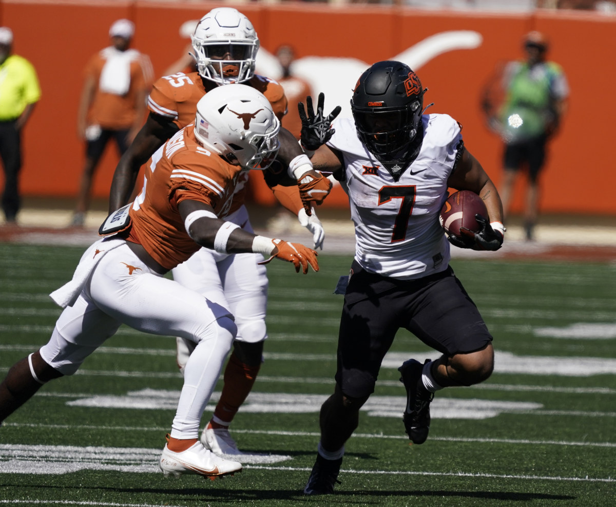 Oct 16, 2021; Austin, Texas, USA; Oklahoma State Cowboys running back Jaylen Warren (7) tries to avoid a tackle by Texas Longhorns defensive back D'Shawn Jamison (5) while running for yardage in the second half of the game at Darrell K Royal-Texas Memorial Stadium. Mandatory Credit: Scott Wachter-USA TODAY Sports