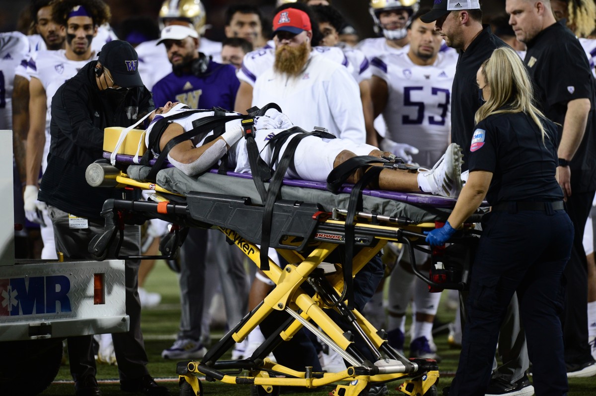 Alex Cook leaves on a cart with an injury, something UW teammate MJ Tafisi (53) experienced in Tucson 24 months earlier.