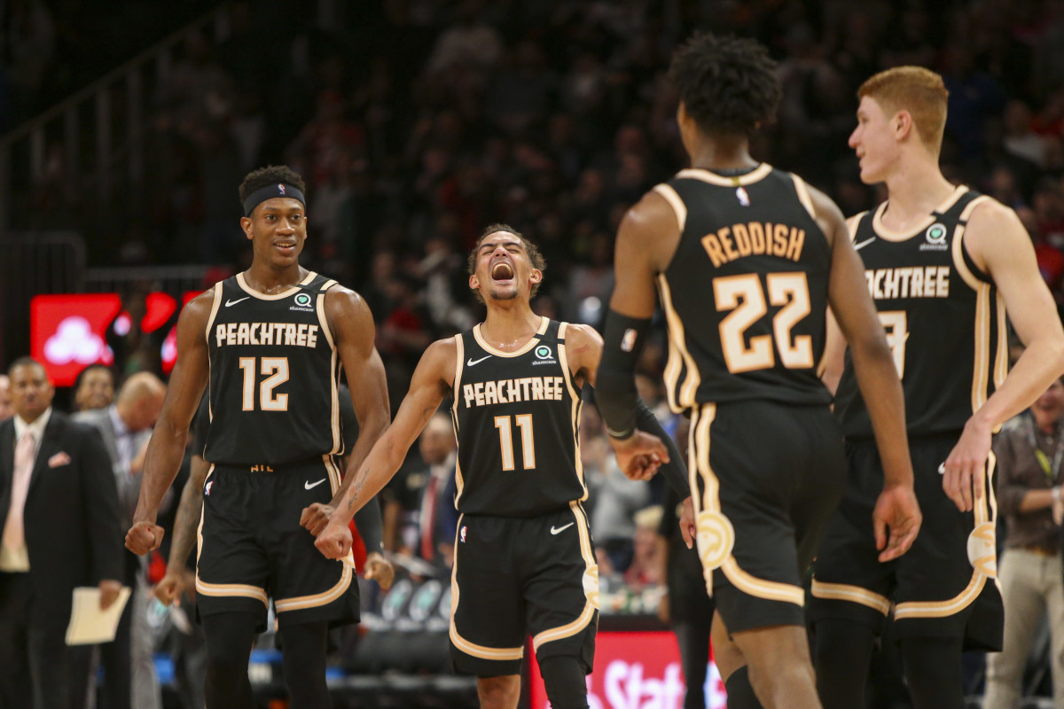Atlanta Hawks guard Trae Young (11) celebrates with forward De'Andre Hunter (12) and guard Kevin Huerter (3) after a basket by guard Cam Reddish (22) against the Miami Heat in the second half at State Farm Arena.