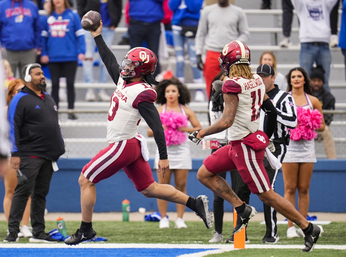 Oct 23, 2021; Lawrence, Kansas, USA; Oklahoma Sooners quarterback Caleb Williams (13) scores a touchdown as wide receiver Jadon Haselwood (11) looks on during the second half against the Kansas Jayhawks at David Booth Kansas Memorial Stadium.