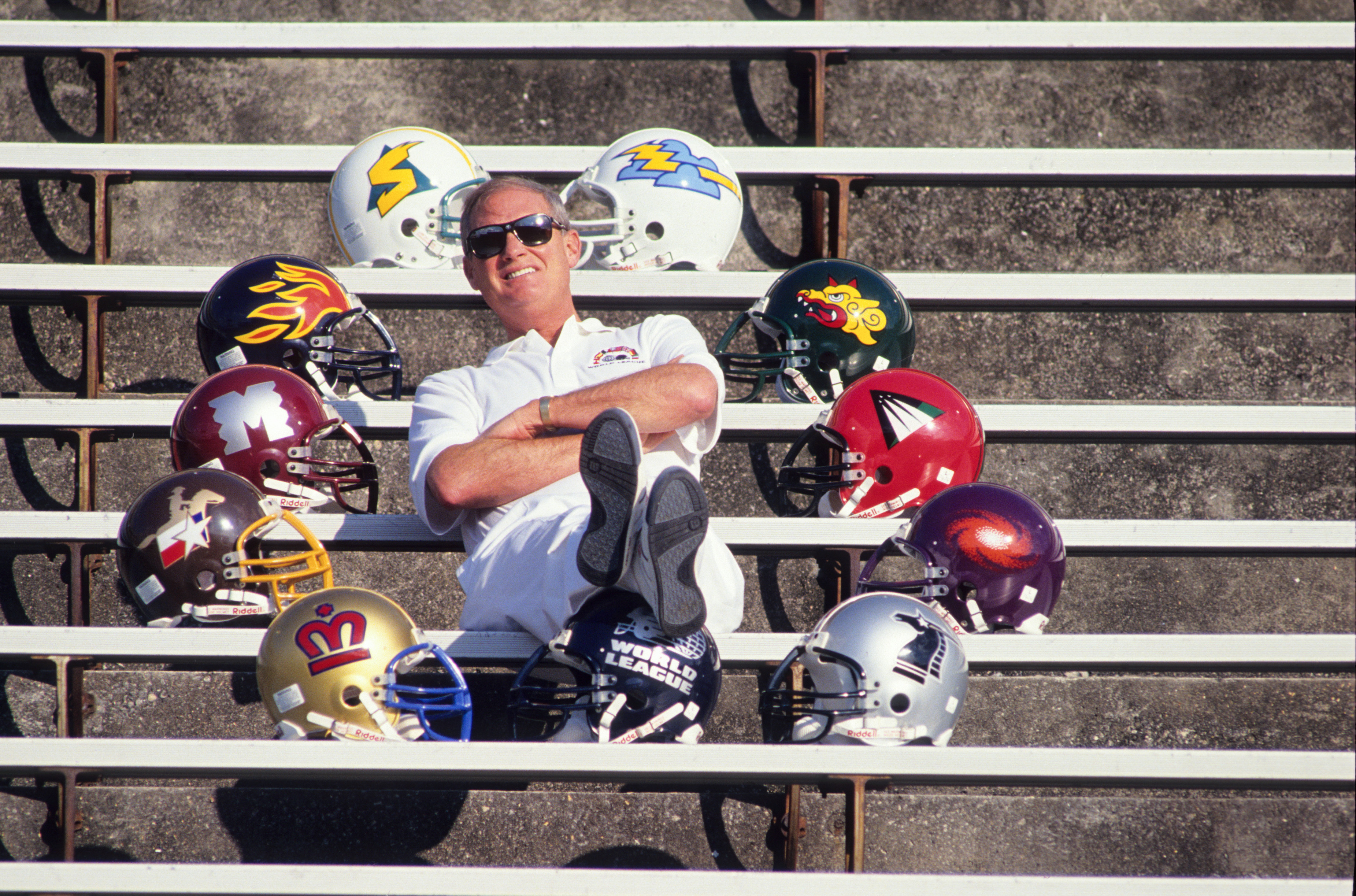 World League commissioner Mike Lynn poses with the helmets of the league's first 10 teams