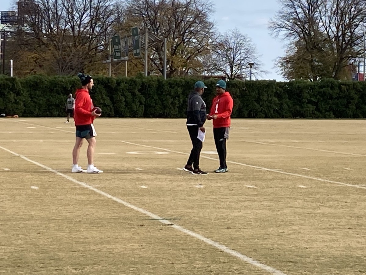 Eagles Jalen Hurts (right) talks with QB coach Brian Johnson as Reid Sinnett looks on during practice on Nov. 17, 2021