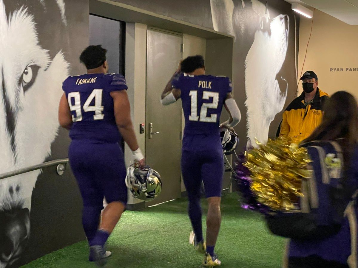 Defensive tackle Taki Taimani and wide receiver Ja'Lynn Polk enter the UW locker room.