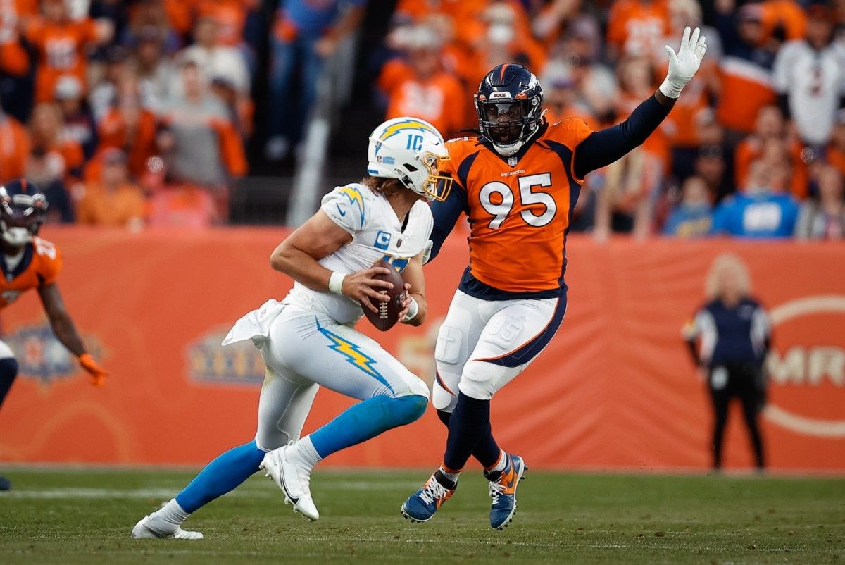 Los Angeles Chargers quarterback Justin Herbert (10) looks to pass under pressure from Denver Broncos defensive tackle McTelvin Agim (95) in the third quarter at Empower Field at Mile High.