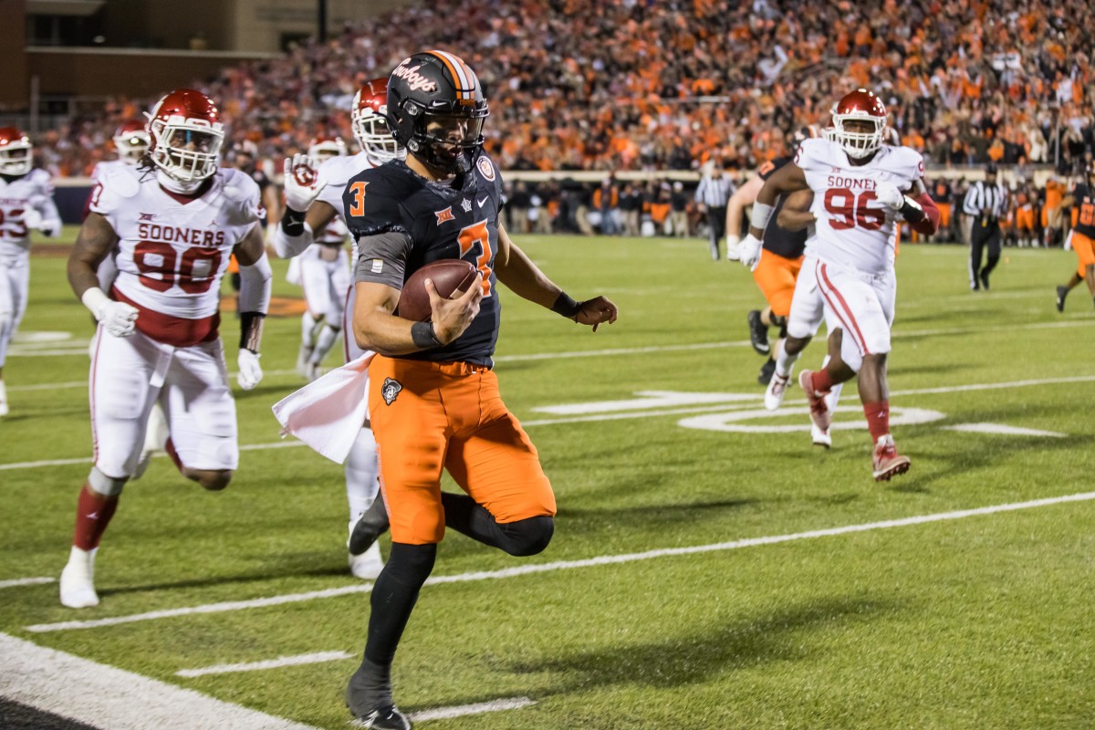 Nov 27, 2021; Stillwater, Oklahoma, USA; Oklahoma State Cowboys quarterback Spencer Sanders (3) runs along the sidelines to scores a touchdown against the Oklahoma Sooners during the fourth quarter at Boone Pickens Stadium. Oklahoma State won 37-33.