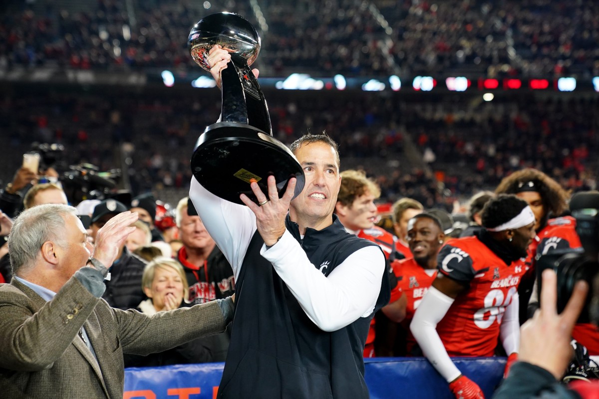 Cincinnati Bearcats head coach Luke Fickell raises the trophy of the American Athletic Conference championship football game, Saturday, Dec. 4, 2021, at Nippert Stadium in Cincinnati. The Cincinnati Bearcats defeated the Houston Cougars, 35-20. Houston Cougars At Cincinnati Bearcats Aac Championship Dec 4