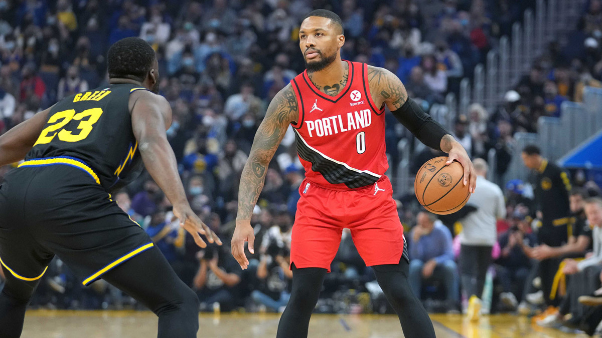 Portland Trail Blazers guard Damian Lillard (0) dribbles while being defended by Golden State Warriors forward Draymond Green.