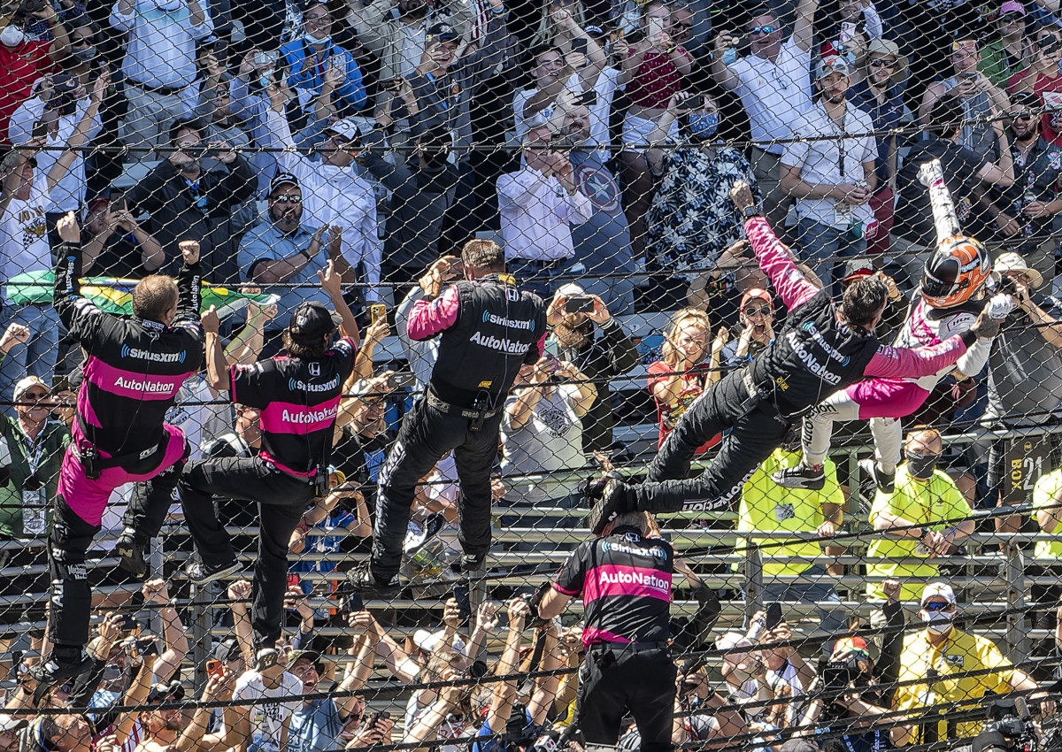 Helio Castroneves celebrates his Indianapolis 500 victory by climbing the fence at Indianapolis Motor Speedway.