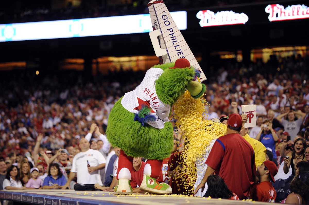 Philadelphia Phillies mascot the Phillie Phanatic dumps a large container of popcorn on an actor dressed as a New York Mets fan in the seventh inning at Citizens Bank Park.