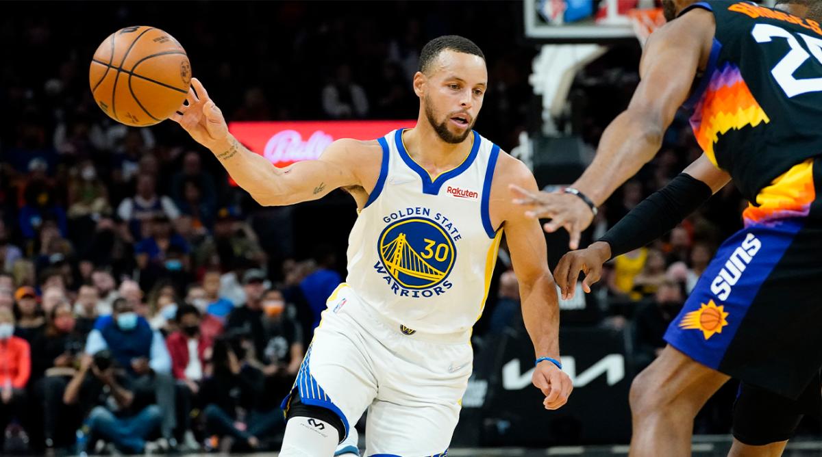 Golden State Warriors guard Stephen Curry (30) dishes off against the Phoenix Suns during the first half of an NBA basketball game, Tuesday, Nov. 30, 2021, in Phoenix.