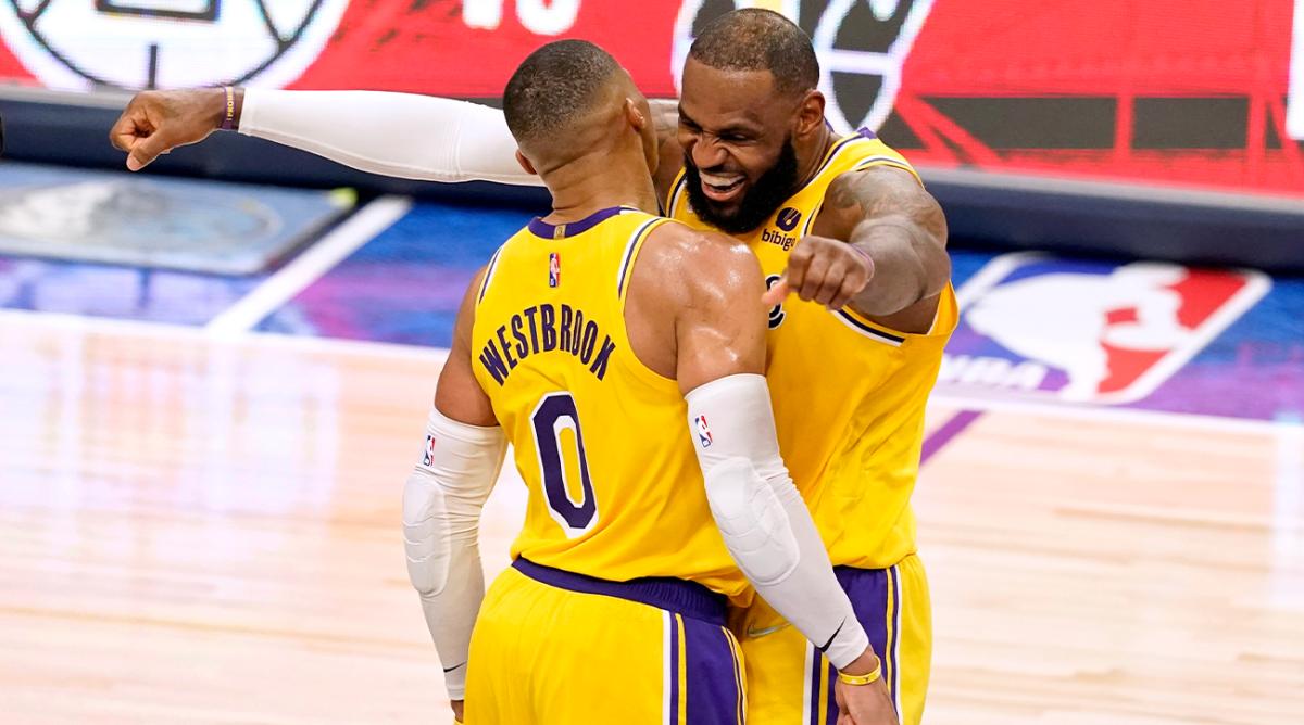 Los Angeles Lakers guard Russell Westbrook (0) and LeBron James, right, celebrate after Westbrook scored a 3-point basket during overtime of an NBA basketball game against the Dallas Mavericks in Dallas, Wednesday, Dec. 15, 2021.