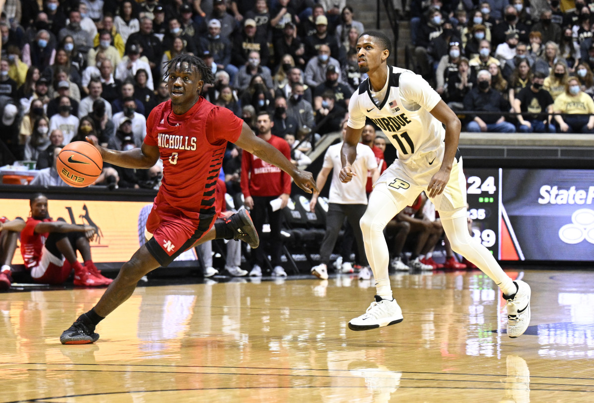 A Nicholls State player dribbles the ball around Isaiah Thompson.