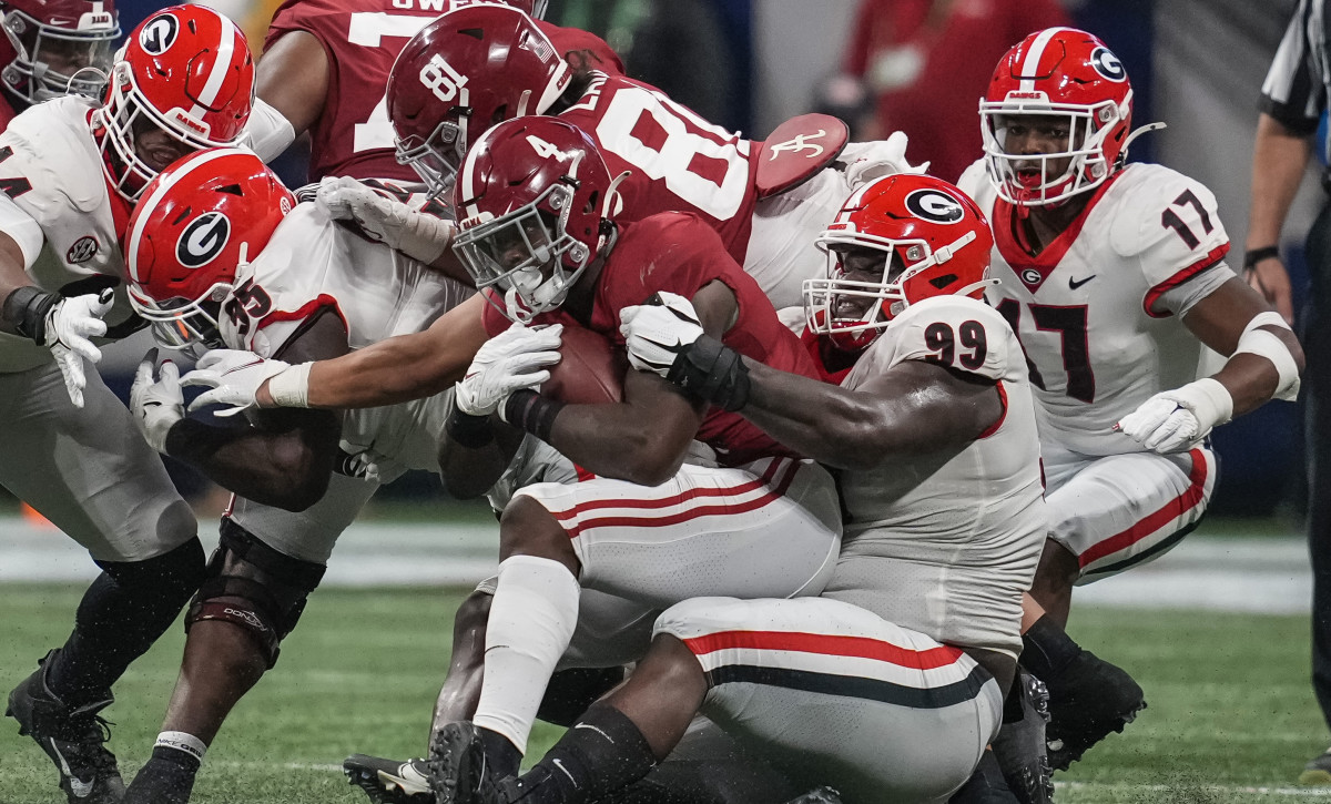 Alabama Crimson Tide running back Brian Robinson Jr. (4) is tackled by Georgia Bulldogs defensive lineman Jordan Davis (99) during the first half at Mercedes-Benz Stadium.