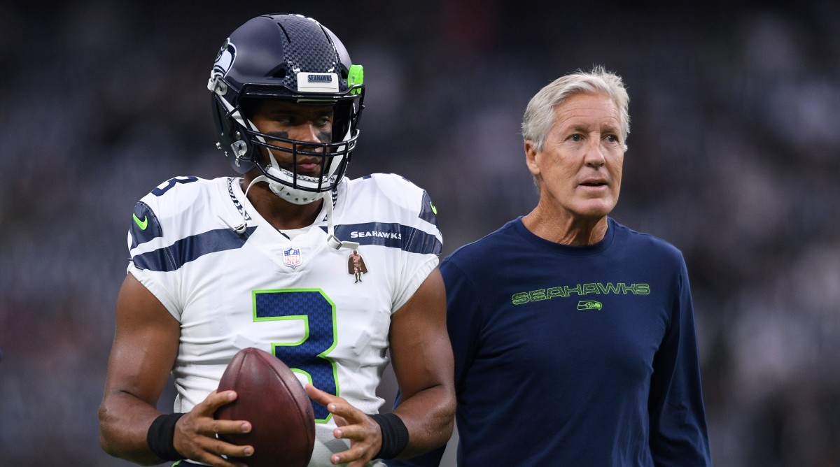 Pete Carroll and Russell Wilson stand on the field together.